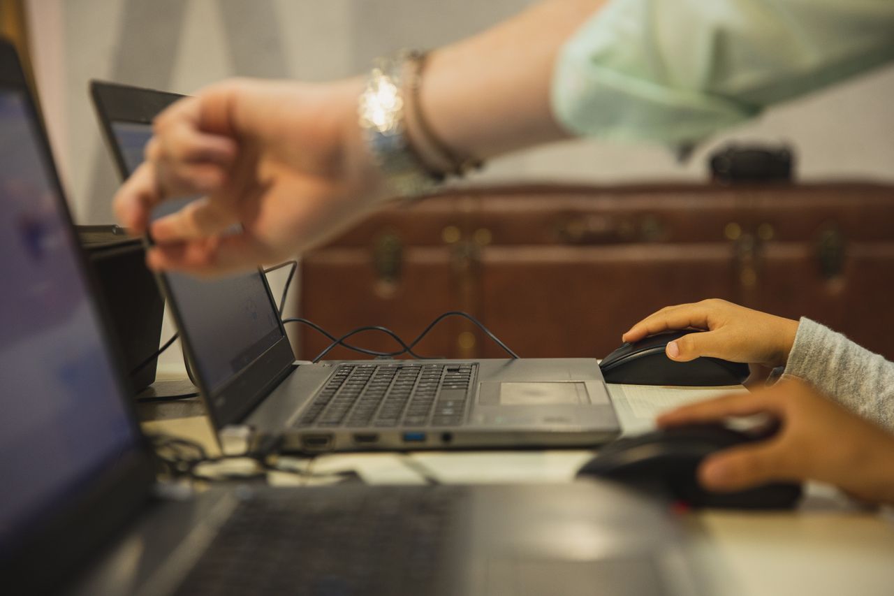 why-choose-us Crop anonymous female teacher pointing at netbook screen near schoolchildren touching mouses at desk in classroom